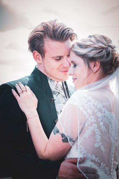 Brautpaar umarmt sich, verliebt, mit sanften Farben und einem romantischen Hintergrund.